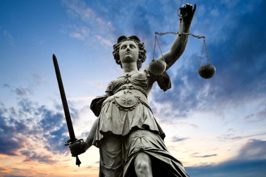 Justicija - Rimska boginja pravde i pravednosti, vezanih očiju u desnoj ruci drži mač, a u levoj vagu.